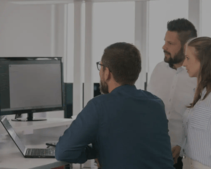 Drei Personen betrachten gemeinsam die Eticor Software auf einem Monitor am Arbeitsplatz.